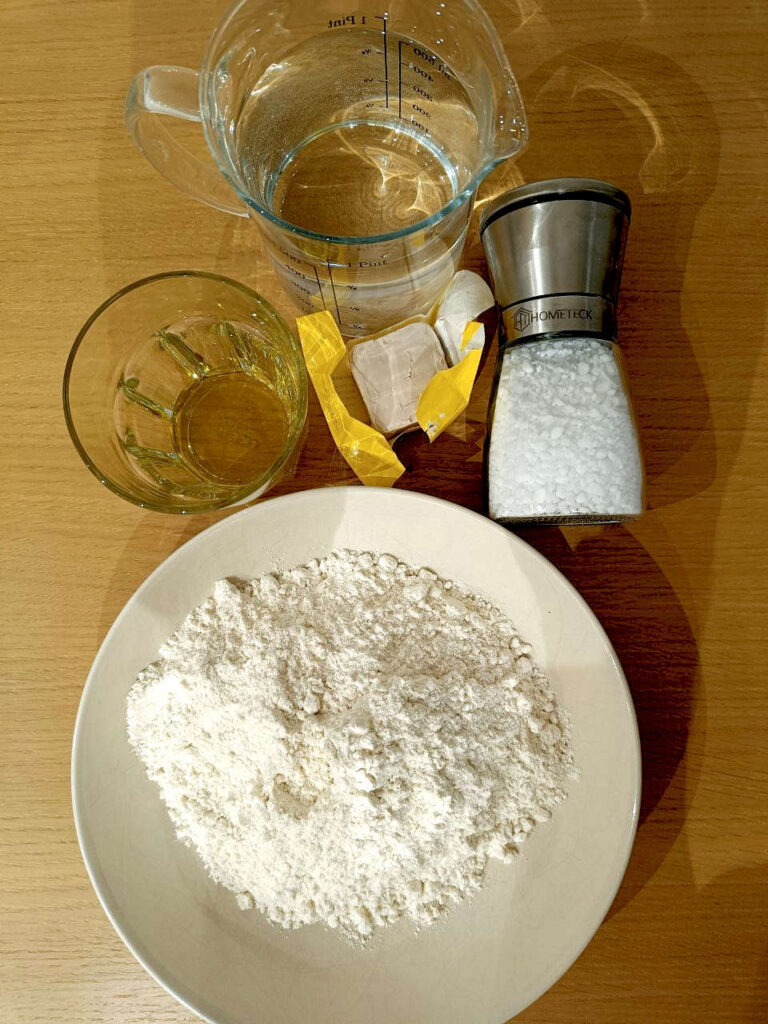 Flour, Oil, Salt, Yeast and Water laid out on a table.