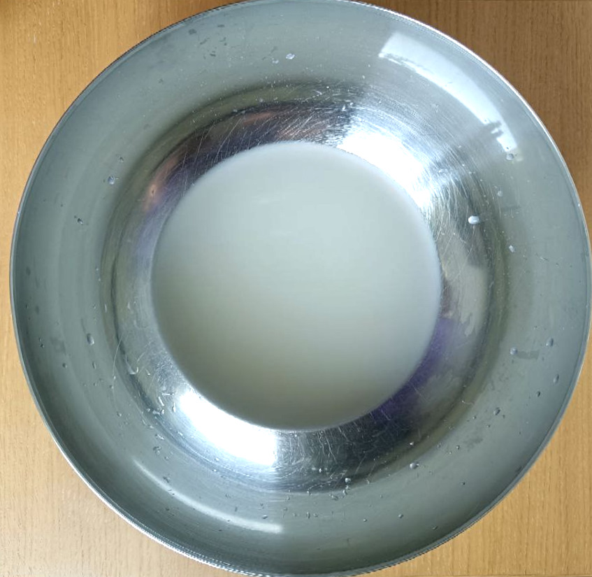 Water with yeast dissolved in it. The water looks murky due to the yeast.