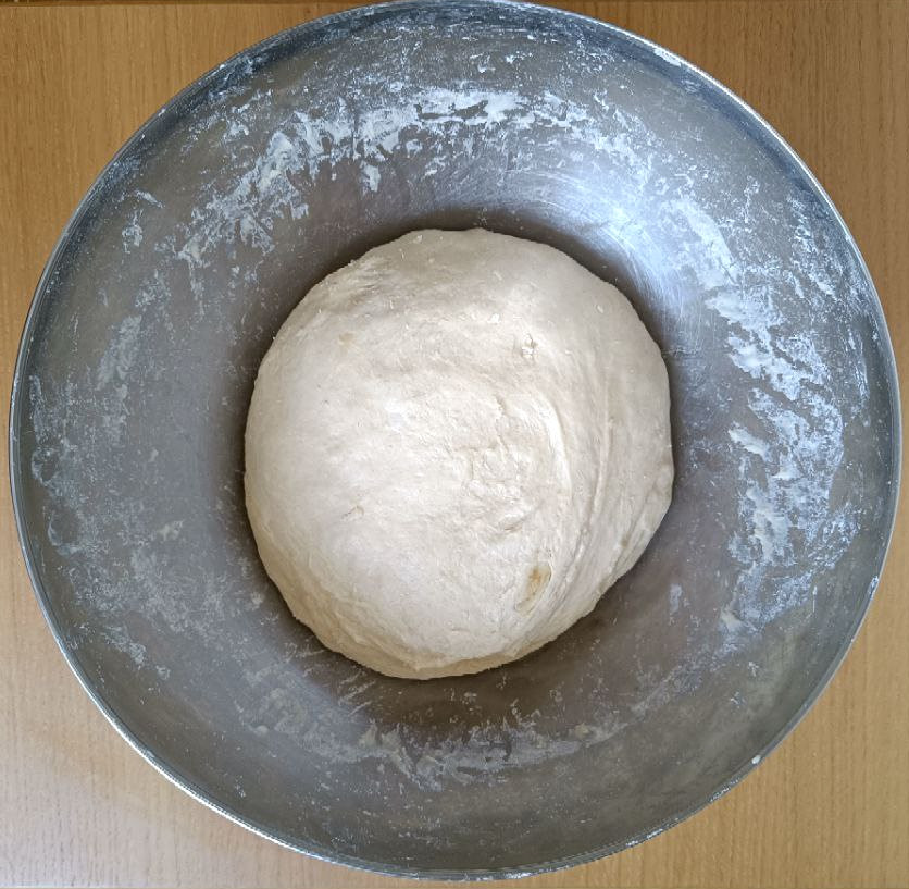 A ball of pizza dough after all ingredients have been mixed. The consistency is uniform and it looks smooth.