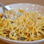 A plate of Pasta alla Carbonara, topped with Pecorino Romano.